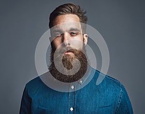 Bearded man in blue denim with tired expression