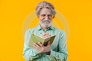 Bearded man in blue shirt writing notes in notebook