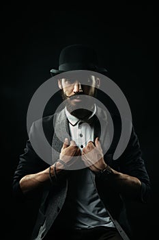 The bearded man in a bowler hat holding his lapels