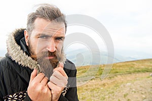 Bearded man, brutal caucasian hipster with moustache cold on mountain