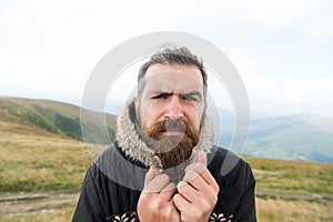 Bearded man, brutal caucasian hipster with moustache cold on mountain