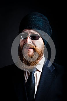 Bearded man businessman middle-aged in black sunglasses and a black knitted hat looks with a reproachful and ironic