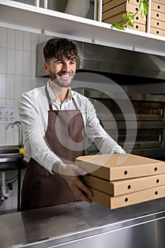 Bearded man cafe employee handing stack of pizza boxes to client