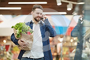 Bearded Man Calling by Smartphone in Supermarket