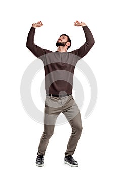 A bearded man in casual clothes attempts to hold something heavy from above on a white background.