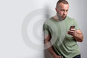 Bearded man in casual clothes looking at phone on white background