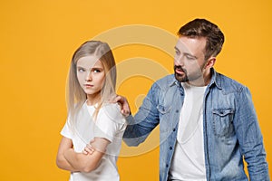 Bearded man in casual clothes with offended child baby girl. Father little kid daughter isolated on yellow background