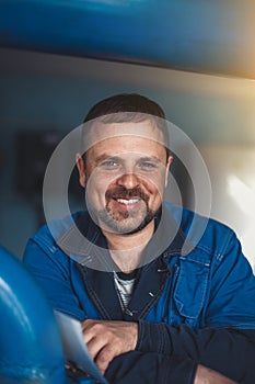 A bearded man of Caucasian appearance smiles a snow-white smile. Happy workplace worker