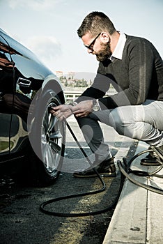 Bearded man checking tire pressure