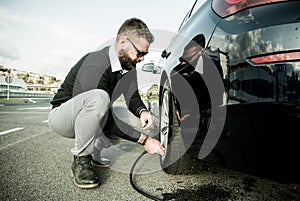 Bearded man checking tire pressure