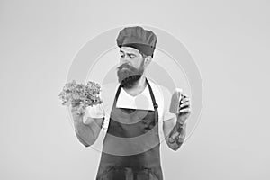 Bearded man chef in apron and hat. hipster decide what to choose. healthy eating and dieting concept. cook hold fresh