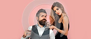 Bearded man with classic beard drinkind whiskey, bearded man and sexy woman with scissors. Barber with scissor