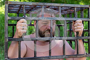 A bearded man clings to jail, wants to limit himself. The concept of bad habits and vices, alcoholism, gambling photo