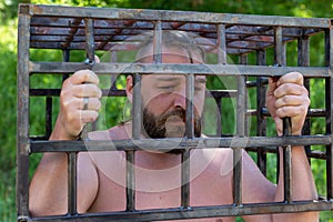 A bearded man clings to jail, wants to limit himself. The concept of bad habits and vices, alcoholism, gambling