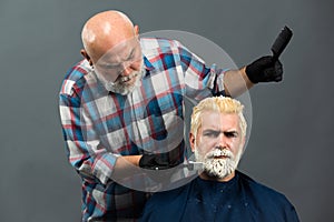 Bearded man coloring hair. Hair salon, hair coloring man. Attractive senior barber doing a haircut and haircolor for