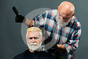 Bearded man coloring hair. Hair salon, hair coloring man. Attractive senior barber doing a haircut and haircolor for