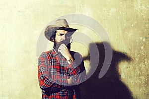 Bearded man in cowboy hat and black shadow on wall
