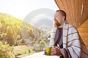 Bearded man with a cup in the morning in a mountain resort