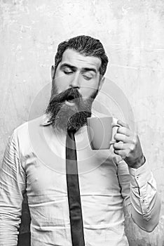Bearded man with curious face look into tea, coffee cup
