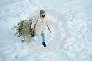 Bearded Man cutting Christmas tree. Happy father with Christmas tree on a snowy winter walk. Hipster woodsman with