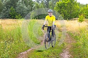 bearded man cyclist in yellow clothes rides a bike on a road in nature. sports, hobbies and entertainment for health
