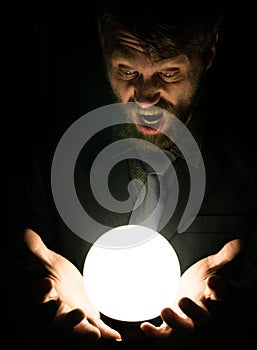 Bearded man in the dark, holding in front of a lamp, expresses different emotions