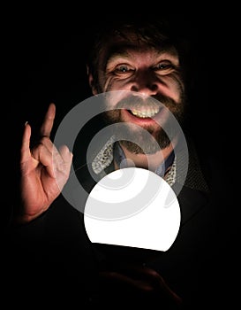 Bearded man in the dark, holding in front of a lamp, expresses different emotions. showing thumbs up sign heavy metal
