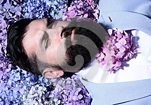 A bearded man with a decorated beard for the Spring holiday. Flower in the beard. Bearded man with beard in flover in