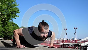 The bearded man is doing push ups during his morning outdoor training. Urban fitness training.