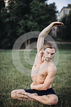 Bearded man doing yoga in the green park.