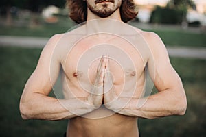 Bearded man doing yoga in the green park. Closeup.