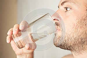 Bearded man drinks water from a glass