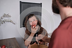 Bearded man eating apple while talking to his friend