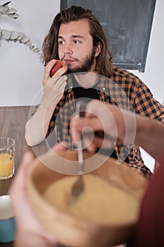 Bearded man eating apple while talking to his friend