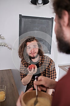 Bearded man eating apple while talking to his friend