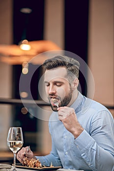Bearded man eating seafood at the restaurant and looking involved
