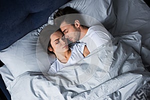 Bearded man embracing attractive brunette woman while sleeping