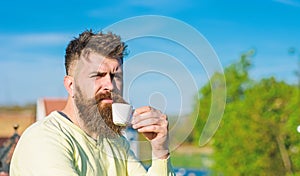 Bearded man with espresso mug, drinks coffee. Coffee break concept. Man with long beard looks strict and serious. Man