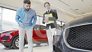 Bearded man examining new car on sale at the dealership