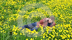 Bearded man in field of yellow dandelions talking on the phone
