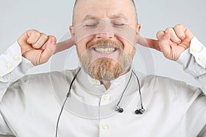 Bearded man with fingers in his ears instead of headphones
