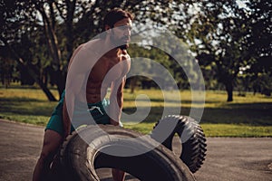 Bearded man flipping tires in the park