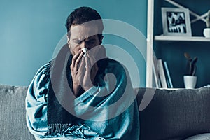 Bearded Man with Flue Sitting on Sofa at Home.