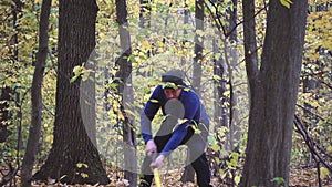 Bearded man in the forest with an ax slowing down.