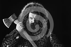 Bearded man in fur with axe on black background, copy space