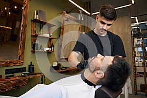 Bearded man getting beard haircut by barber at barbershop