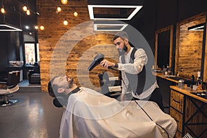 Bearded man getting beard haircut by hairdresser at barbershop.