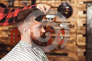 Bearded man getting haircut by hairdresser. Brutal guy sitting in barber chair
