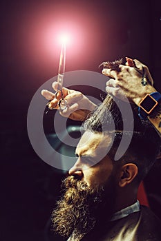 Bearded man getting stylish hair cutting with scissors