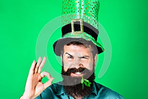 Bearded man in green top hat with clover in mouth showing sign ok. Saint Patrick's day celebration. National Irish